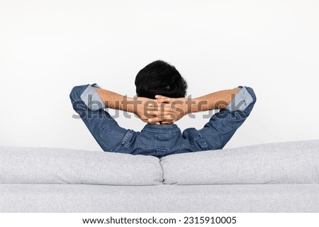 Back view of relaxed brunette man wearing casual comfy outfit resting on couch at home, sitting on sofa with hands behind head, copy space, enjoy his new house, resting at weekend, white background