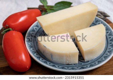Italian cheese, Provolone dolce cow cheese from Cremona served with olive bread and tomatoes close up. Royalty-Free Stock Photo #2315915351