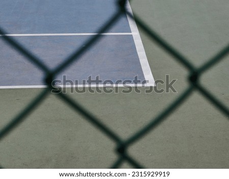 Diamond shapes. Grid, green fence. Framed, tennis court. Blue floor, white lines. Details. Sport for recreation.