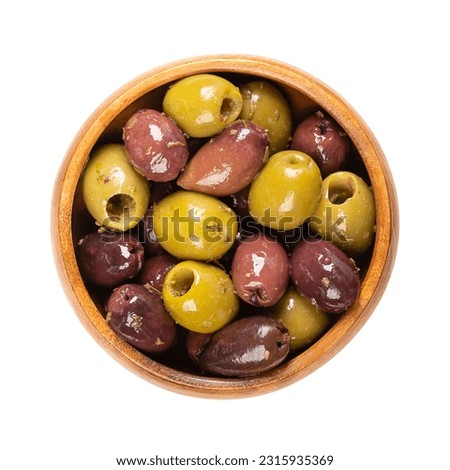 Pitted Kalamata and green olives, in a wooden bowl. Mix of organic Greek olives, green and black, with herbs, preserved in native olive oil. Popular table olives, used as snack, appetizer or garnish. Royalty-Free Stock Photo #2315935369