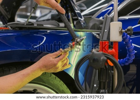 Removal of dents without painting. PDR technology for car body repair. PDR. The mechanic at the auto shop with tools to repair dents in car body. Body repair. Royalty-Free Stock Photo #2315937923
