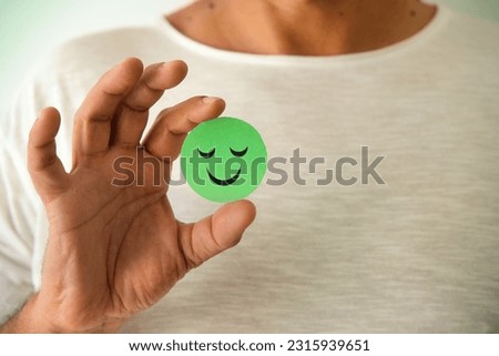 Man holding a positive green emoji. Smile, satisfaction. Copy space. Royalty-Free Stock Photo #2315939651