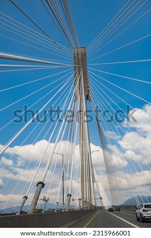 Modern bridge pylon against a blue sky. Detail of the multi-span cable-stayed bridge. Linear perspective view of a white cable-stayed suspension Alex Fraiser Bridge in BC. Nobody, selective focus Royalty-Free Stock Photo #2315966001