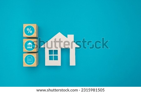 Property investment and house mortgage financial. House made of paper and wooden cubes with search, interest, and bank icons is on a blue background. Home loan and risk management