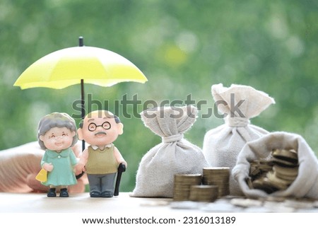 Mutual fund,Love couple senior and hand holding the umbrella with stack of coins money on natural green background, Save money for prepare in future and pension retirement concept