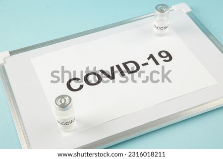 Front close view of a sheet with COVID- and medicine ampoules on white desk on blue background