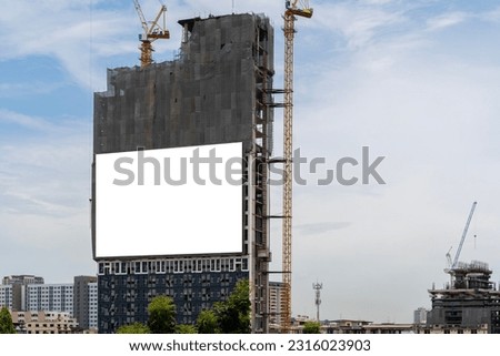 Blank white banner for advertisement hanging on the scaffolding of modern building under construction. Blank white advertising banner on the wall of modern office building under construction