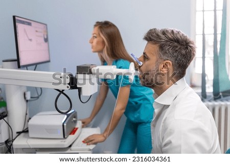 Man performing pulmonary function test and spirometry using spirometer at medical clinic. Spirometry of lungs Royalty-Free Stock Photo #2316034361