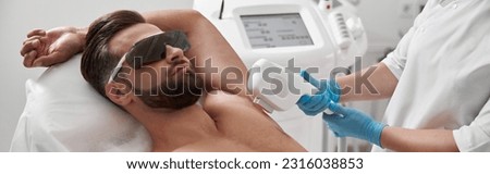 Man with goggles and bare chest undergoes procedure of arm pit laser epilation in clinic