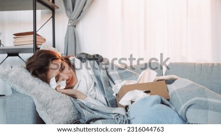 Home fever. Sick woman. Unhealthy girl wrapped plaid laying sofa with napkin influenza symptoms suffering high temperature runny nose frowning face room interior. Royalty-Free Stock Photo #2316044763