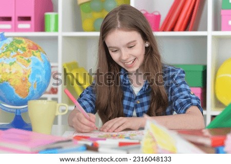 cute girl drawing picture at home at the table