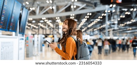 Young asian woman in international airport, using mobile smartphone and checking flight at the flight information board Royalty-Free Stock Photo #2316054333