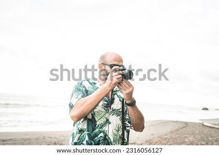 Photo with copy space of a man taking pictures with digital camera on a tropical beach