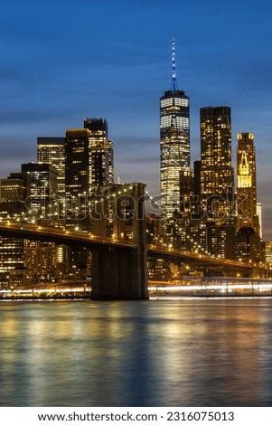 New York City skyline of Manhattan with Brooklyn Bridge and World Trade Center skyscraper at twilight night portrait format in the United States
