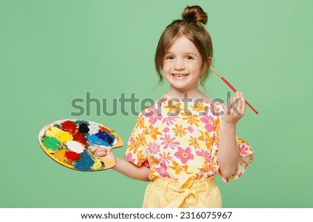 Little creative child kid girl 6-7 years old wear casual clothes have fun paint hold palette with paints isolated on plain pastel green background studio. Mother's Day love family lifestyle concept Royalty-Free Stock Photo #2316075967