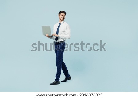 Full body side view young employee IT business man corporate lawyer wearing classic formal shirt tie work in office hold use work on laptop pc computer isolated on plain pastel blue background studio