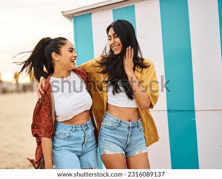 Portrait of two beautiful cheerful young women resting  on the beach. Laughing girlfriends in the sea side having fun
