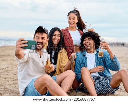 Group of young cheerful people having fun and drinking beer, taking selfie photo with mobile phone camera at the party on the beach looking happy, Enjoying youth and freedom concept