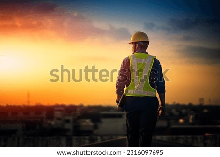 Engineer on a construction site at sunset. Working on the roof .  Royalty-Free Stock Photo #2316097695