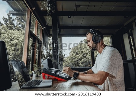 Young man using synth pads, make music Royalty-Free Stock Photo #2316119433