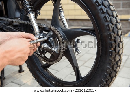 man checking moped wheel before riding Royalty-Free Stock Photo #2316120057