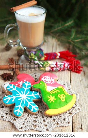 Homemade gingerbreads in the form of a snowflake and a green horse on a wooden table and a glass of warm cacao with a small knit scarf. Selective Focus on gingerbreads. Toned