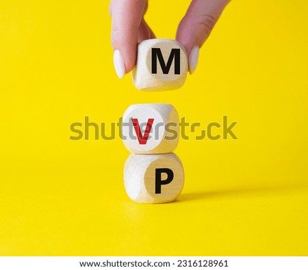 MVP - Most Valuable Player symbol. Wooden cubes with words MVP. Businessman hand. Beautiful yellow background. Business and MVP concept. Copy space.