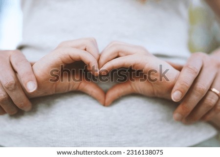 Children's hands in the shape of a heart on the background of mother's belly, pregnancy.
