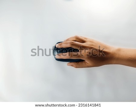 A hand holding a small black mouse on a white background, isolated.