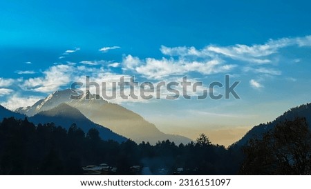 A beautiful Sunrise between mesmerising mountains, And that blue and white  sky is add more calmness in the view.