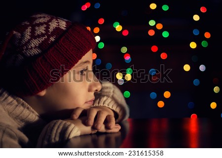 Little boy in a red cap in anticipation of Christmas. Christmas expectation.