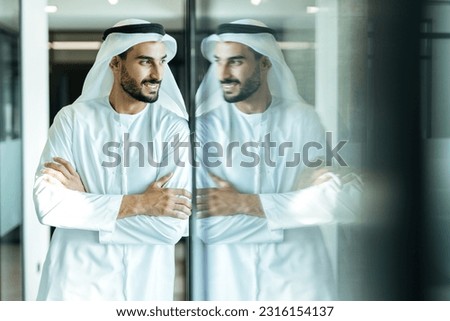 handsome man with dish dasha working in his business office of Dubai. Portraits of a successful businessman in traditional emirates white dress. Concept about middle eastern cultures Royalty-Free Stock Photo #2316154137
