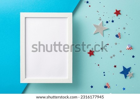 USA Freedom Day festive artistic greetings. Top view of emblematic embellishments: glittering stars, glistening confetti on bicolor blue surface with an empty photo frame for text or picture