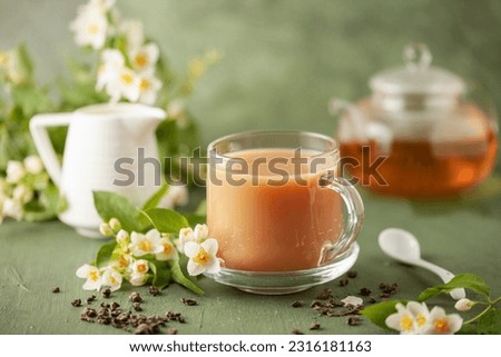 Composition with cup of jasmine milk tea and flowers on green background Royalty-Free Stock Photo #2316181163