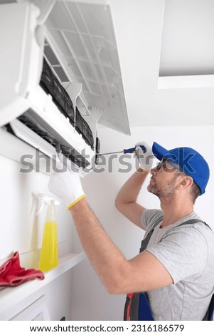 Service guy cleaning and maintaining air condition unit. Royalty-Free Stock Photo #2316186579