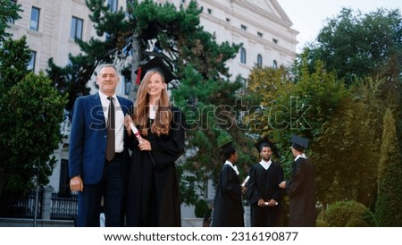 In the college garden beautiful lady student graduate posing excited with her diploma with the college professor in front of the camera