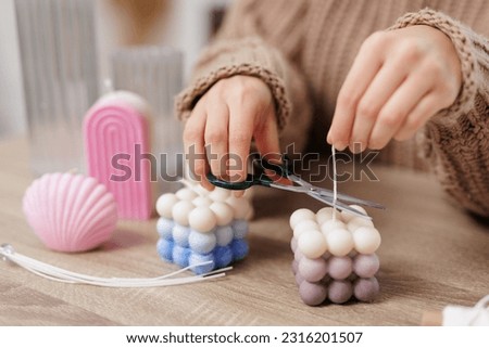 Close up of female hands cutting wick of bauble candle on table