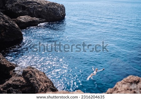 Vacation. Young woman swimming and bathing at sea rock lagoon.