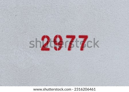 Red Number 2977 on the white wall. Spray paint.
