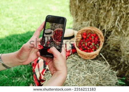 Woman taking picture on her Phone of basket with strawberries