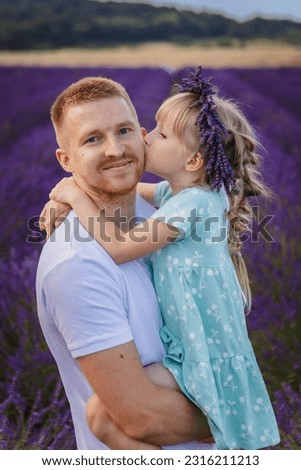 daughter kisses dad on the cheek. a happy father holds a child in his arms