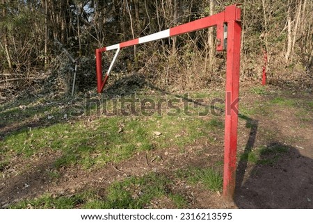 Red metal barrier with white stripes in the forest