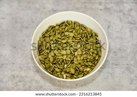 Roasted pumpkin seeds (pepitas) in a white bowl.