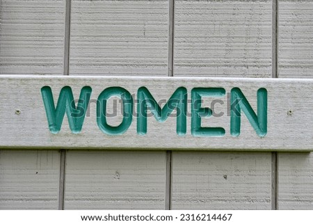 A close view of the wood women restroom sign.