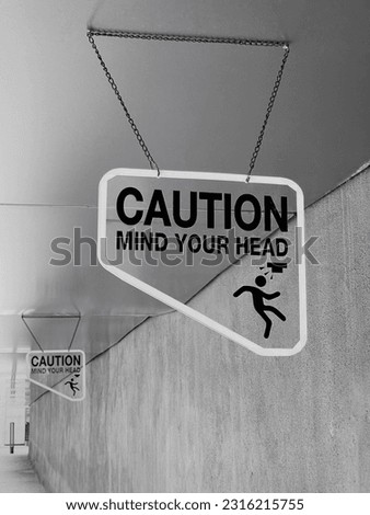 Black and white image of Caution Mind Your Head signage, one of safety control measure of hazardous areas or parts of a building.