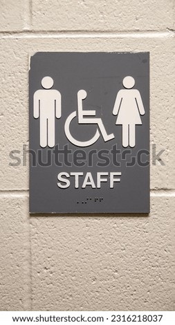 A closeup of staff restroom sign hanging on a white wall