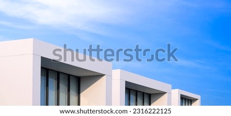 Row of white townhouse buildings with balconies in modern style against blue sky background in panoramic view  Royalty-Free Stock Photo #2316222125
