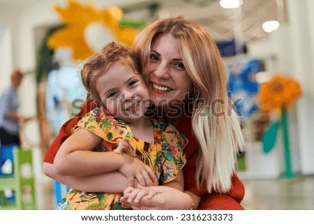 A cute little girl kissing and hugs her mother in preschool