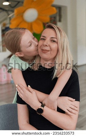A cute little girl kisses and hugs her mother in preschool
