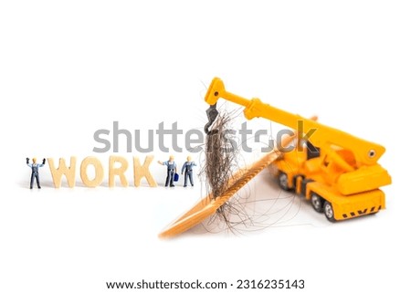 selective focus photo of miniature workers with hair on wooden comb, abstract background to solution hair loss concept.